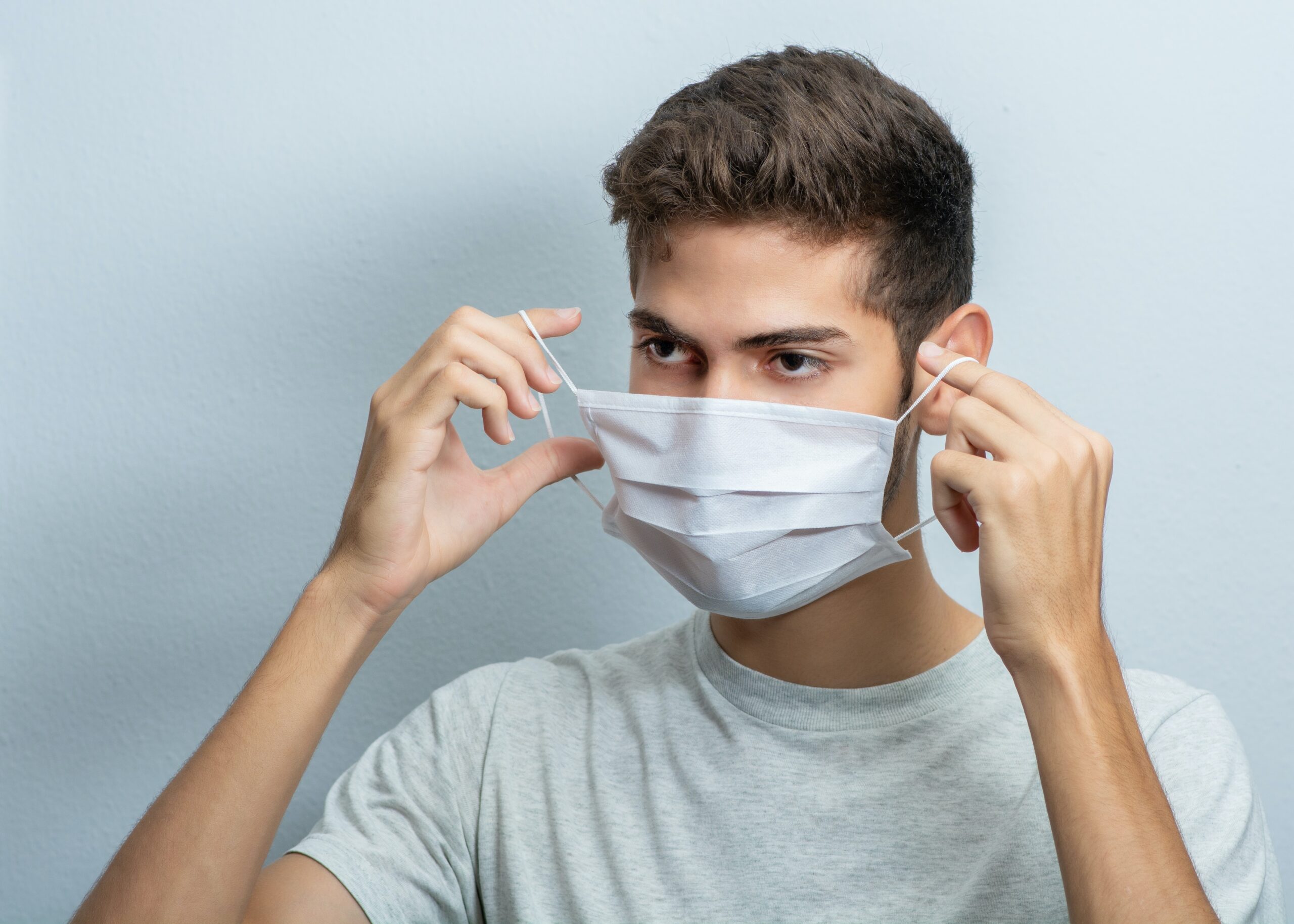 Young man putting on a facemask during Covid 19 pandemic